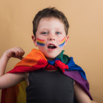 Smiling boy with rainbow flag and striped makeup
