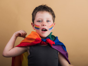 Smiling boy with rainbow flag and striped makeup